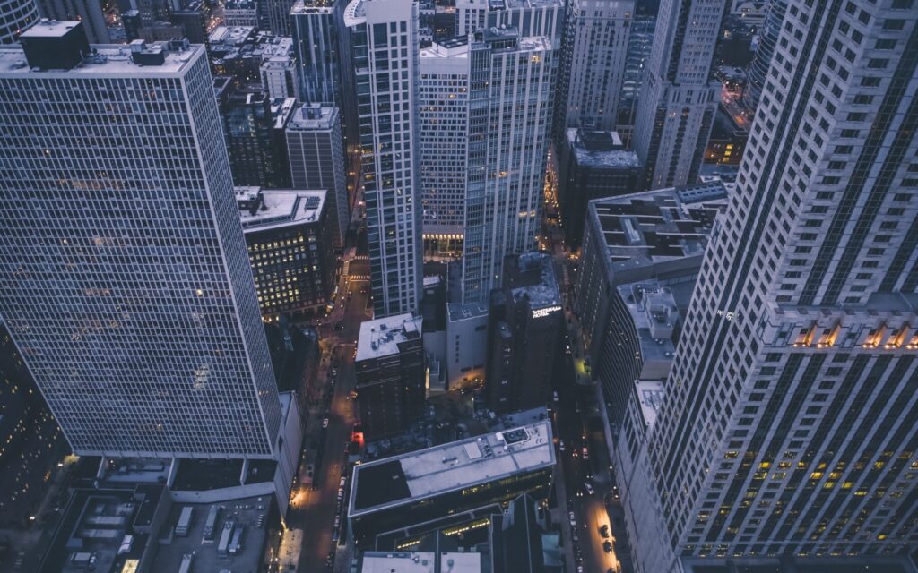 Many large skyscraper exteriors in close proximity at night in city.