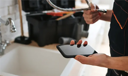 Plumber reviewing details on cell phone during service request.